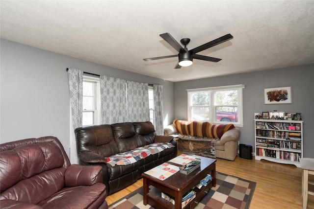 living room with light hardwood / wood-style flooring, ceiling fan, and a textured ceiling