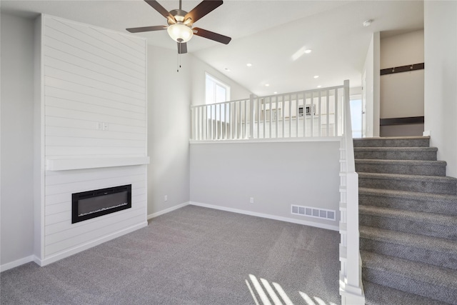 unfurnished living room featuring a glass covered fireplace, carpet flooring, visible vents, and baseboards