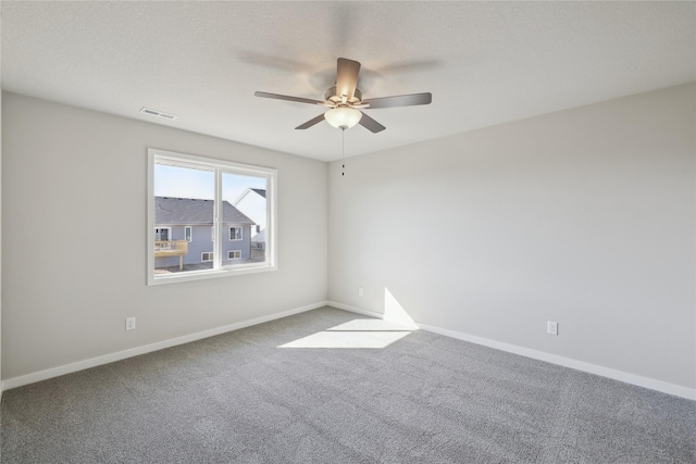 carpeted spare room with a textured ceiling, a ceiling fan, visible vents, and baseboards