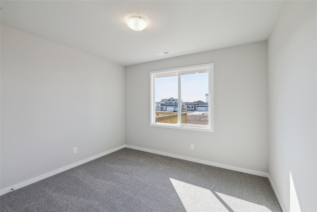 empty room featuring carpet floors, visible vents, and baseboards