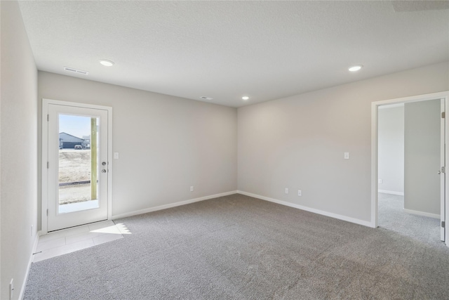 carpeted spare room with a textured ceiling, baseboards, visible vents, and recessed lighting