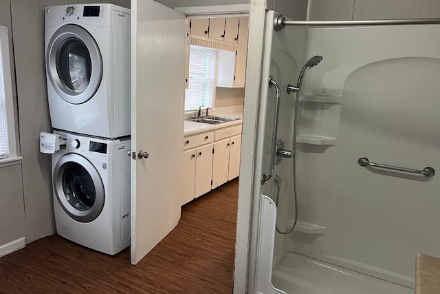 laundry area with stacked washing maching and dryer, sink, and dark wood-type flooring