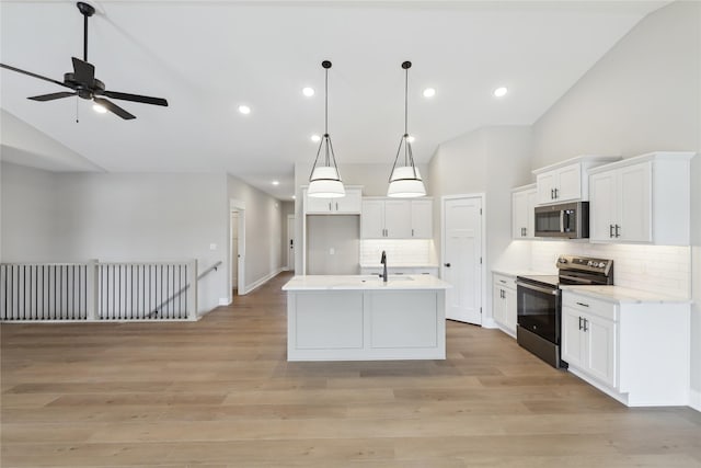 kitchen with backsplash, stainless steel appliances, white cabinetry, hanging light fixtures, and an island with sink