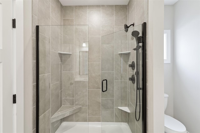 bathroom featuring a shower with shower door and toilet