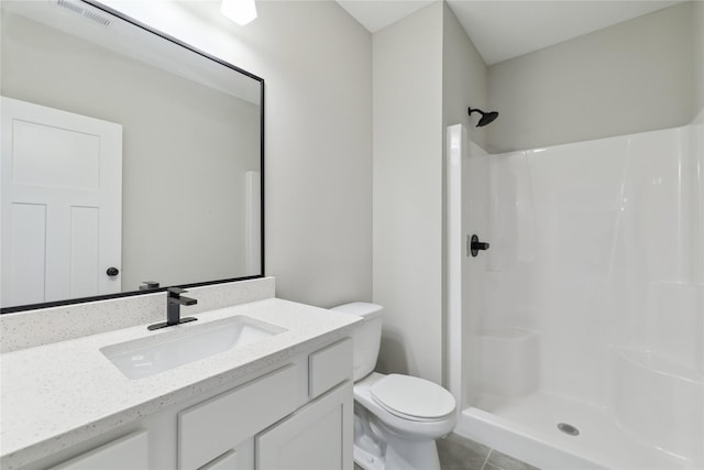 bathroom featuring toilet, vanity, tile patterned floors, and walk in shower