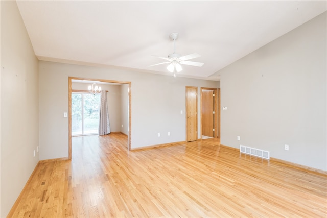 unfurnished room with ceiling fan with notable chandelier and light hardwood / wood-style flooring