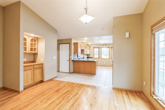 kitchen featuring pendant lighting, light hardwood / wood-style floors, kitchen peninsula, and a healthy amount of sunlight