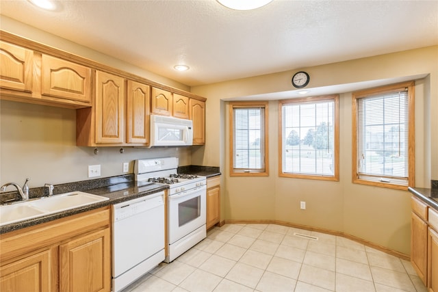 kitchen featuring light tile patterned floors, sink, white appliances, a textured ceiling, and dark stone countertops