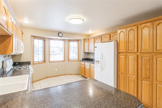 kitchen featuring a textured ceiling, white appliances, sink, and light tile patterned floors