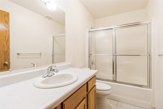 full bathroom featuring tile patterned flooring, toilet, vanity, and bath / shower combo with glass door