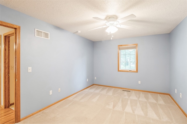 spare room with a textured ceiling, ceiling fan, and light colored carpet