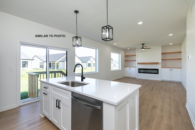 kitchen featuring dishwasher, a kitchen island with sink, white cabinets, hanging light fixtures, and light hardwood / wood-style floors