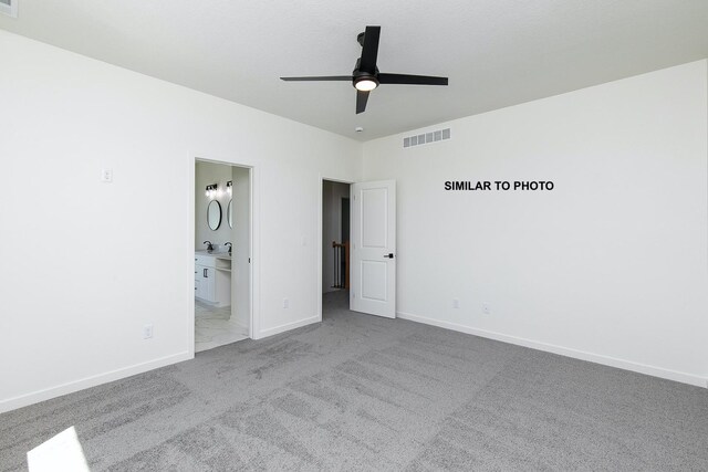 unfurnished bedroom featuring ceiling fan, light colored carpet, and ensuite bath