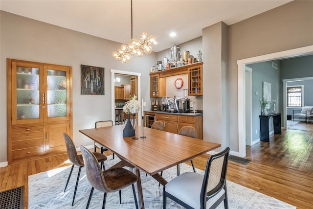 dining space with wine cooler, a chandelier, light hardwood / wood-style floors, and sink