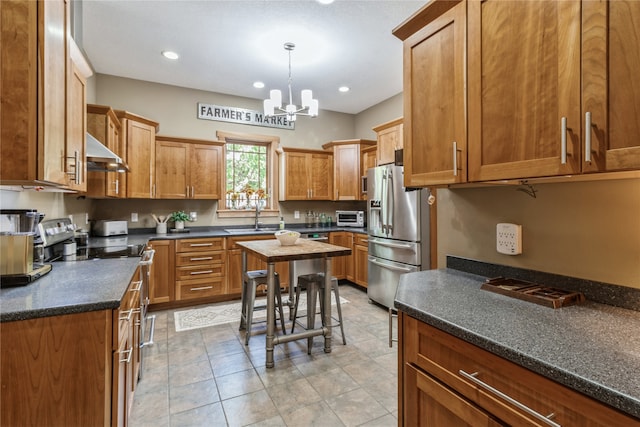 kitchen featuring appliances with stainless steel finishes, range hood, decorative light fixtures, sink, and a chandelier