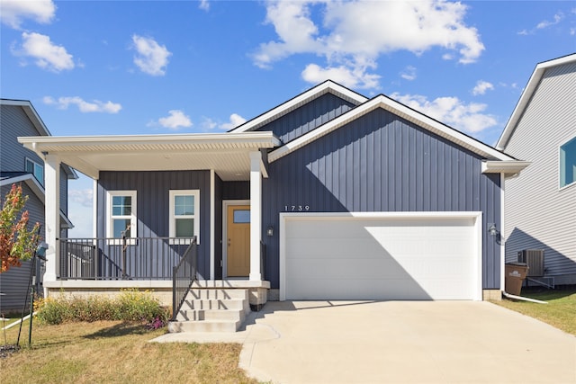 view of front of home featuring a front lawn, covered porch, central AC unit, and a garage