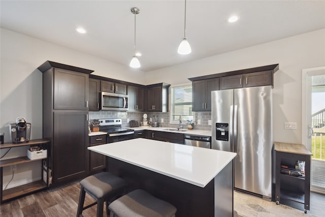 kitchen featuring pendant lighting, sink, stainless steel appliances, a center island, and hardwood / wood-style floors