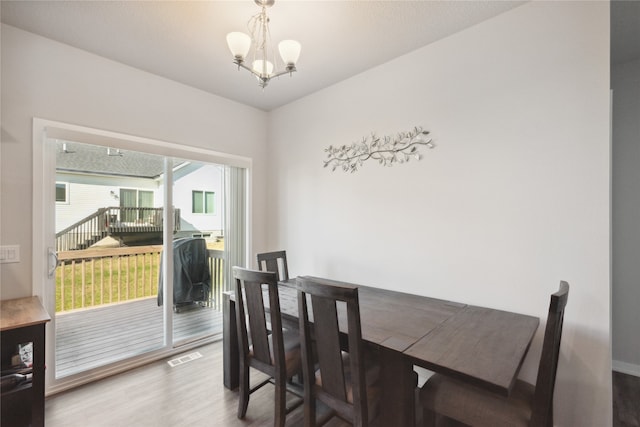 dining space with hardwood / wood-style flooring and a chandelier