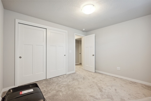 unfurnished bedroom with light colored carpet, a textured ceiling, and a closet