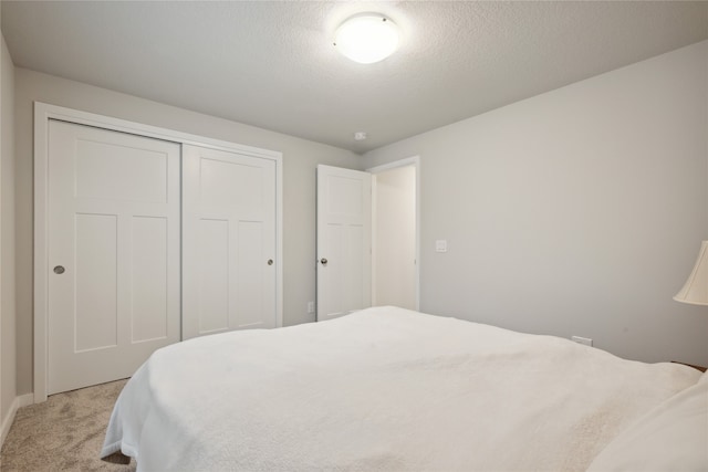 carpeted bedroom with a textured ceiling and a closet