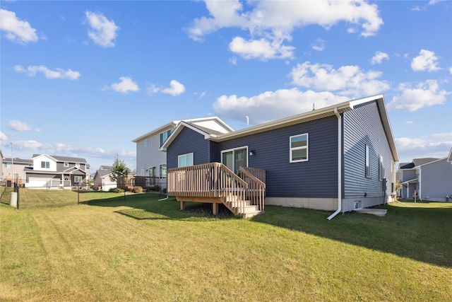 rear view of house featuring a garage, a deck, and a lawn