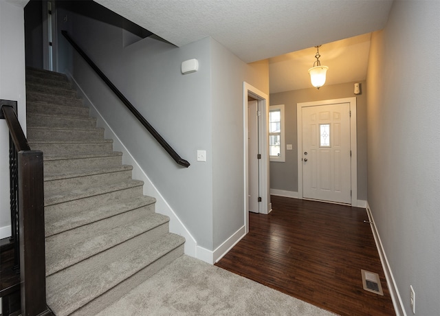 entrance foyer with a textured ceiling and dark hardwood / wood-style floors