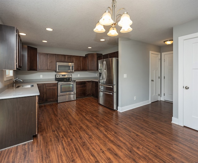 kitchen with appliances with stainless steel finishes, sink, decorative light fixtures, and dark hardwood / wood-style flooring