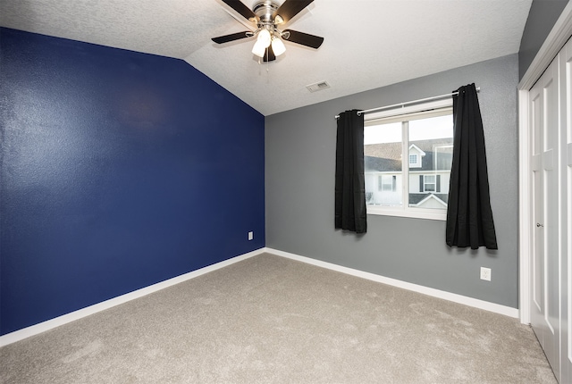 carpeted empty room with ceiling fan, a textured ceiling, and lofted ceiling