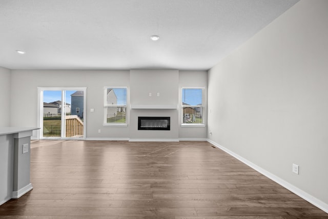 unfurnished living room featuring plenty of natural light and dark hardwood / wood-style flooring