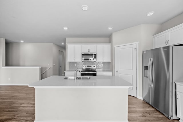 kitchen with appliances with stainless steel finishes, hardwood / wood-style flooring, a kitchen island with sink, and white cabinets