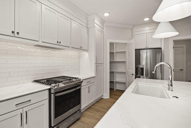 kitchen with white cabinetry, sink, light stone counters, backsplash, and appliances with stainless steel finishes