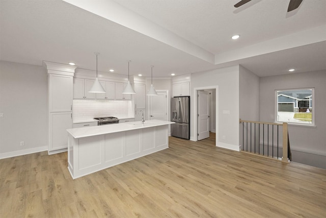 kitchen with white cabinets, pendant lighting, stainless steel appliances, and a center island with sink