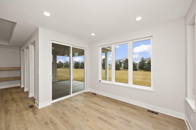 spare room with light wood-type flooring and a textured ceiling