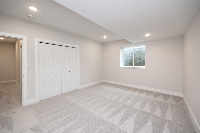 unfurnished bedroom with light colored carpet and a closet