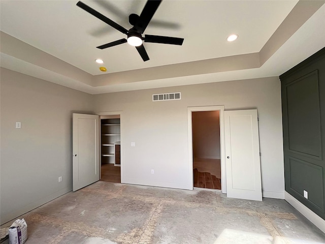 unfurnished bedroom featuring a raised ceiling and ceiling fan