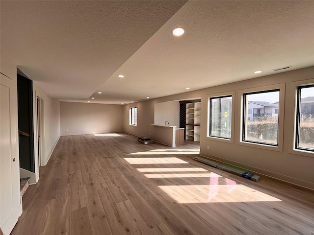 unfurnished living room featuring hardwood / wood-style floors and a textured ceiling