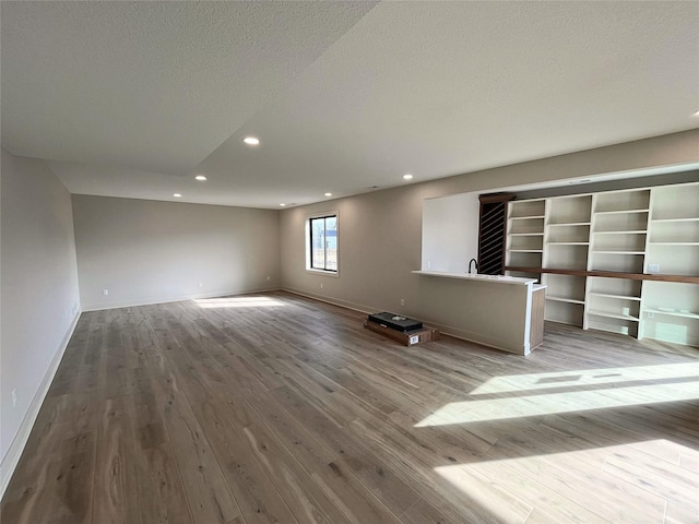 unfurnished living room featuring light hardwood / wood-style floors and a textured ceiling