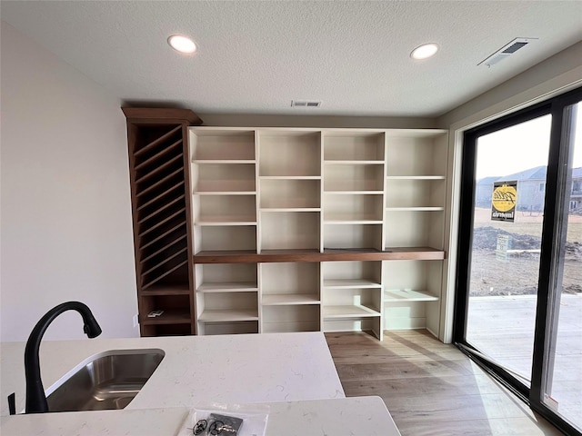 unfurnished office with sink, a textured ceiling, and light hardwood / wood-style floors