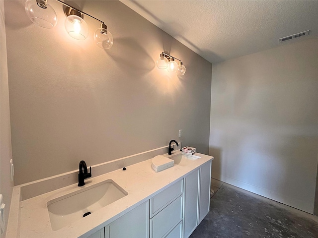 bathroom with concrete flooring, vanity, and a textured ceiling