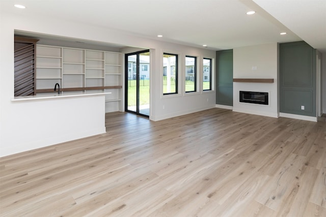 18016 Tanglewood Dr, Clive, IA 50325 - unfurnished living room featuring recessed lighting, light wood-style flooring, and a glass covered fireplace