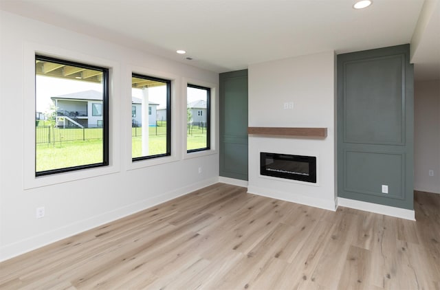 18016 Tanglewood Dr, Clive, IA 50325 - unfurnished living room with light wood-style flooring, recessed lighting, and a glass covered fireplace
