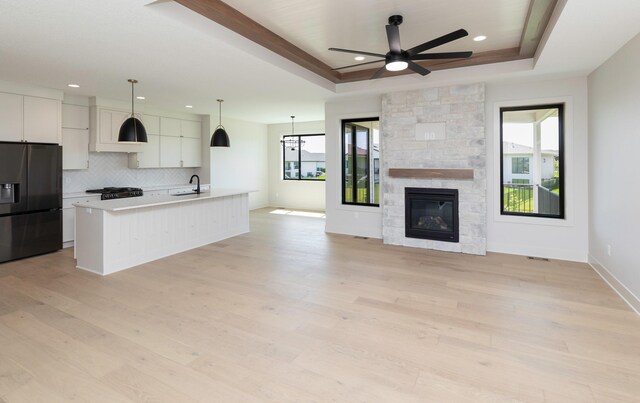 18016 Tanglewood Dr, Clive, IA 50325 - kitchen with black fridge, a raised ceiling, open floor plan, a ceiling fan, and tasteful backsplash