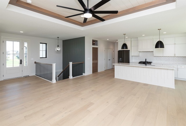 18016 Tanglewood Dr, Clive, IA 50325 - unfurnished living room featuring a raised ceiling, recessed lighting, light wood-type flooring, and a ceiling fan
