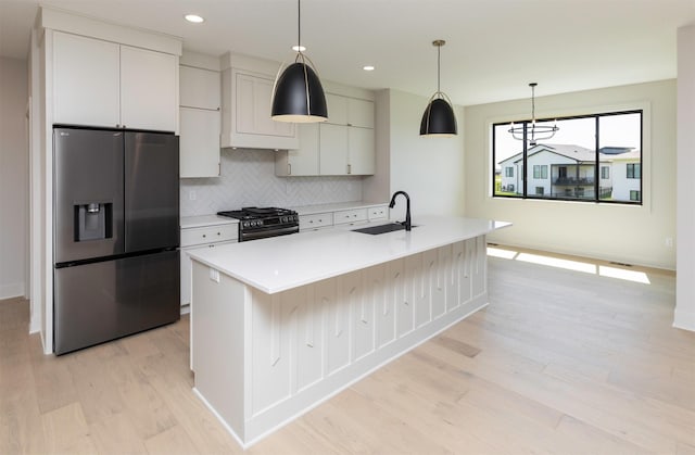 18016 Tanglewood Dr, Clive, IA 50325 - kitchen featuring appliances with stainless steel finishes, light wood-style floors, light countertops, decorative backsplash, and a center island with sink