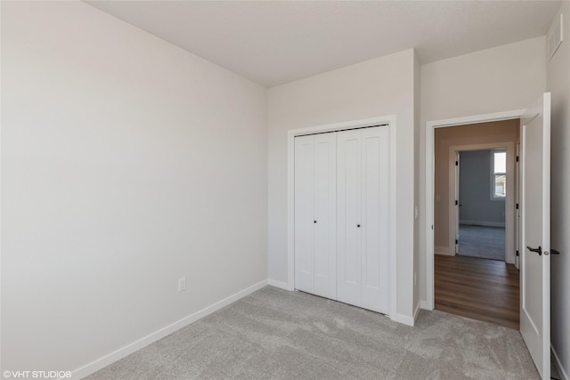 unfurnished bedroom with light carpet and a closet