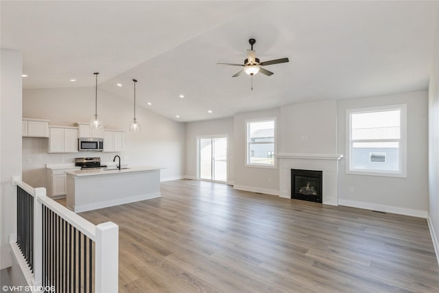 unfurnished living room featuring ceiling fan, light hardwood / wood-style floors, lofted ceiling, and sink