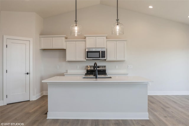 kitchen with a center island with sink, stainless steel appliances, and vaulted ceiling