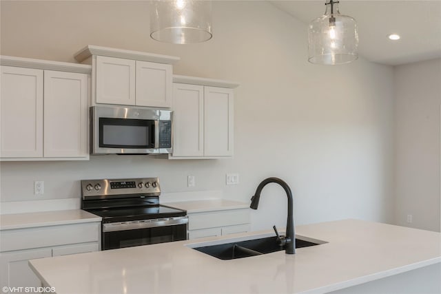 kitchen with appliances with stainless steel finishes, sink, decorative light fixtures, a center island with sink, and white cabinetry