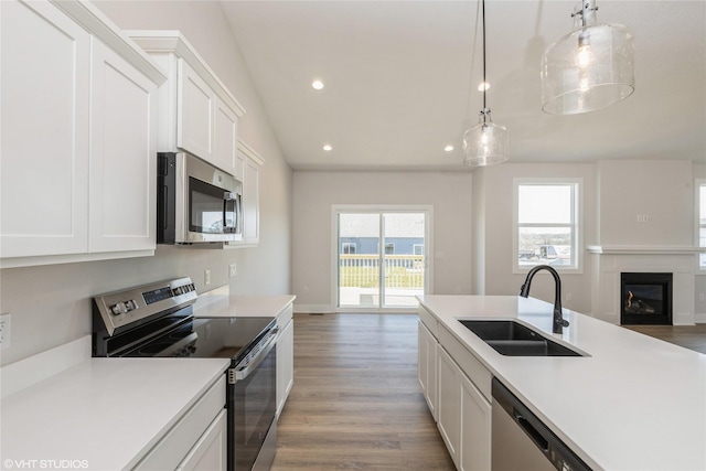 kitchen with hanging light fixtures, white cabinetry, sink, and stainless steel appliances