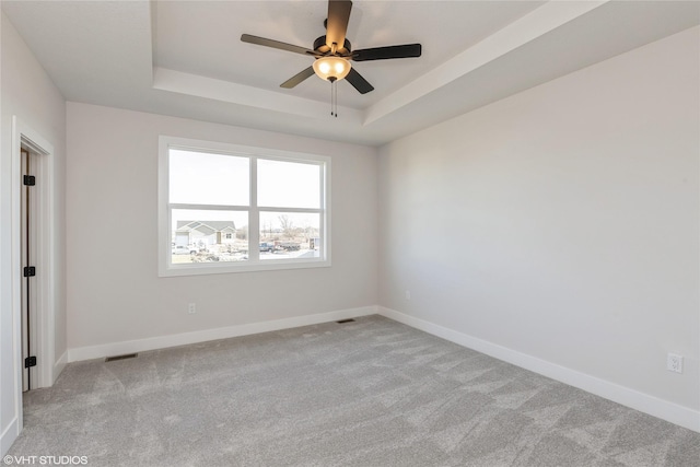 unfurnished room featuring light carpet, a raised ceiling, and ceiling fan